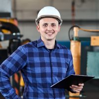 male worker with Hard Hats smile and uses tablet at industrial factory